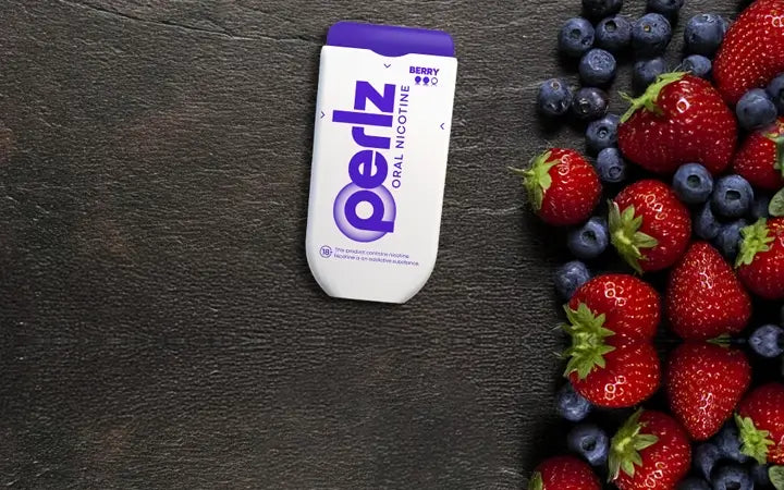 Periz oral nicotine pouch on a dark surface with strawberries and blueberries.